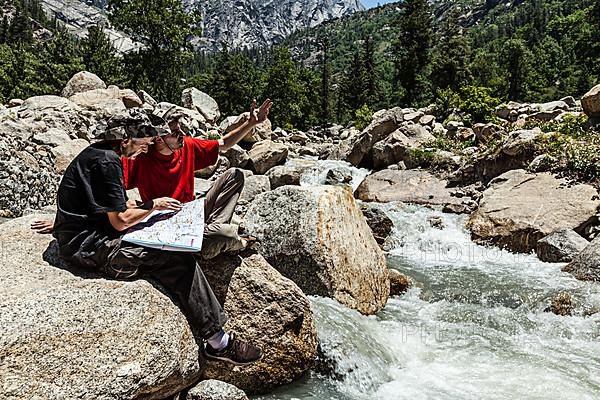 Hiker trekkers read a trekking map on trek in Himalayas mountains. Himachal Pradesh