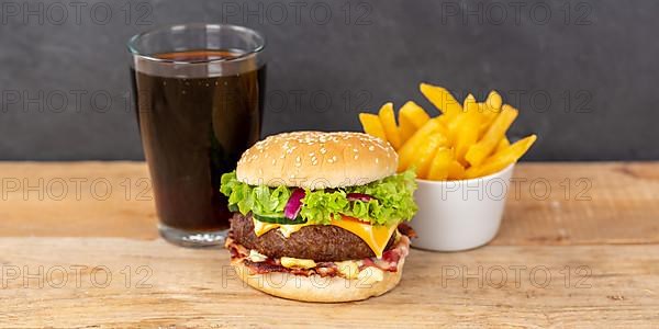 Hamburger cheeseburger fast food meal menu with fries and coke drink on wooden board Panorama in Stuttgart