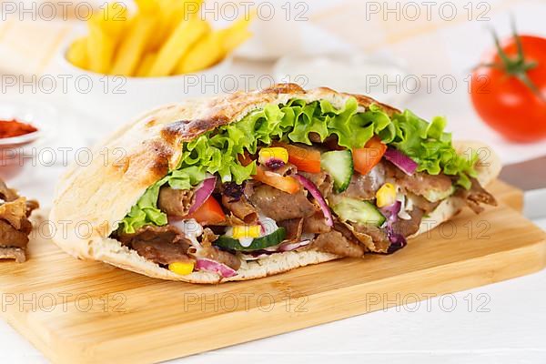 Doener Kebab Doner Kebap half fast food meal in pita bread with fries on wooden board in Stuttgart