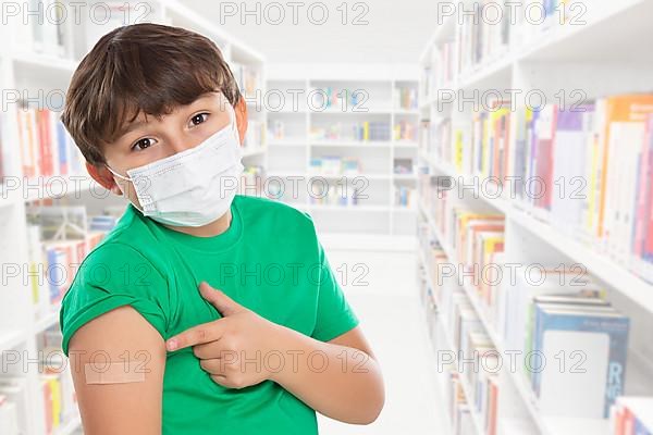 Child boy pointing finger at plaster in school at children vaccination mask against corona virus corona virus text free space copyspace in Stuttgart