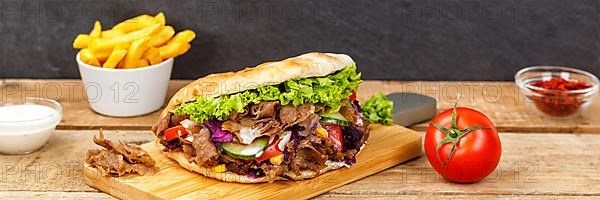 Doener Kebab Doner Kebap fast food meal in pita bread menu with fries on wooden board Panorama in Stuttgart