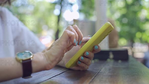 Close up of mature woman's hands use smartphone. Soft focus