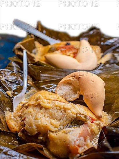 Close up of two Nacatamales in banana leaf served on table. Two Nacatamales served in a banana leaf on a wooden table. Nacatamales with bread served at the table