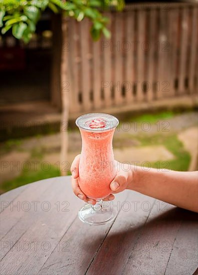 Top view of hand holding a strawberry milkshake on table