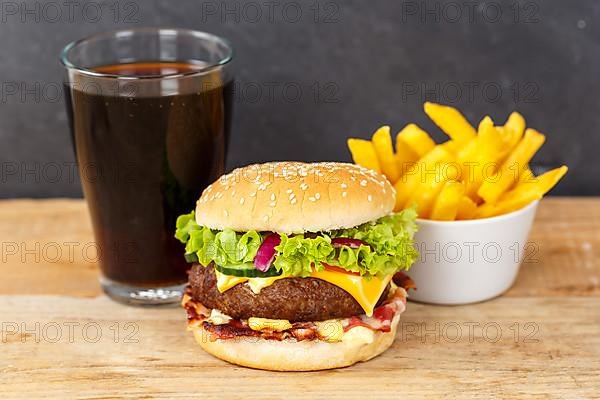 Hamburger cheeseburger fast food meal menu with fries and coke drink on wooden board in Stuttgart