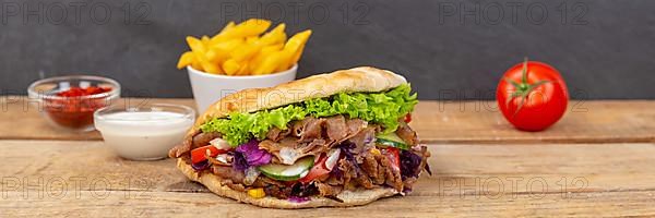 Doener Kebab Doner Kebap fast food meal in pita bread with fries on wooden board Panorama in Stuttgart