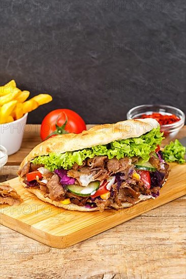 Doener Kebab Doner Kebap fast food meal in pita bread menu with fries on wooden board in Stuttgart