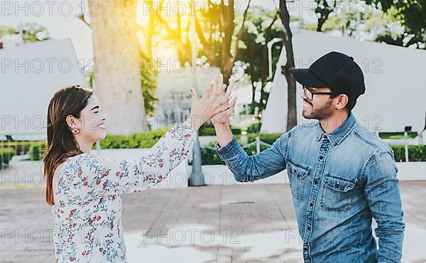 A girl and a guy shaking hands on the street. Two young smiling teenagers shaking hands in the street. Concept of man and woman shaking hands on the street