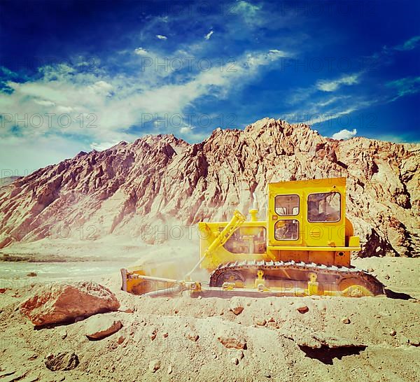 Vintage retro effect filtered hipster style travel image of Bulldozer doing road construction in Himalayas. Ladakh
