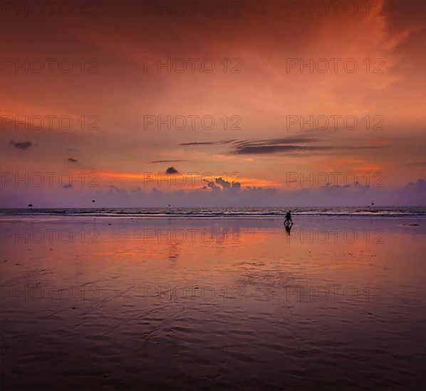 Couple walking on beach on romantic sunset. Baga beach. Goa