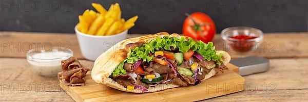 Doener Kebab Doner Kebap half fast food meal in pita bread with fries on wooden board Panorama in Stuttgart