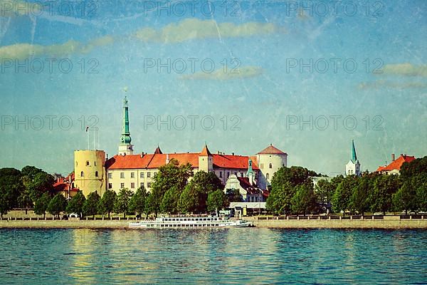 Vintage retro hipster style travel image of View of Riga Castle over Daugava river with grunge texture overlaid. Riga
