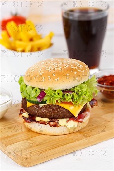 Hamburger cheeseburger fast food meal menu with fries and coke drink on wooden board in Stuttgart