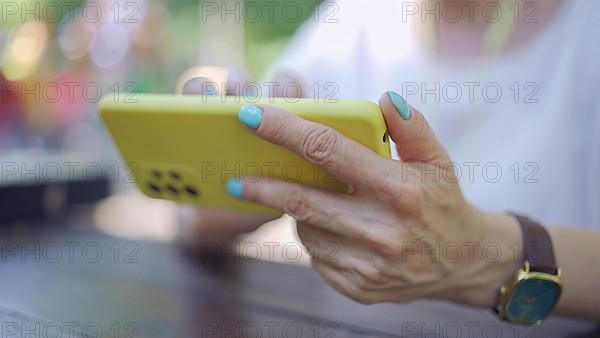 Closeup of mature woman hands playing uses cellphone. Soft focus