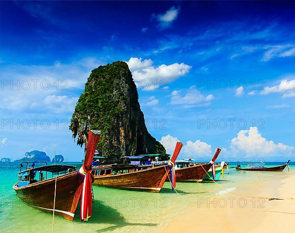 Long tail boat on tropical beach with limestone rock