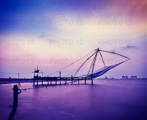 Vintage retro hipster style travel image of Kochi chinese fishnets on sunset. Fort Kochin