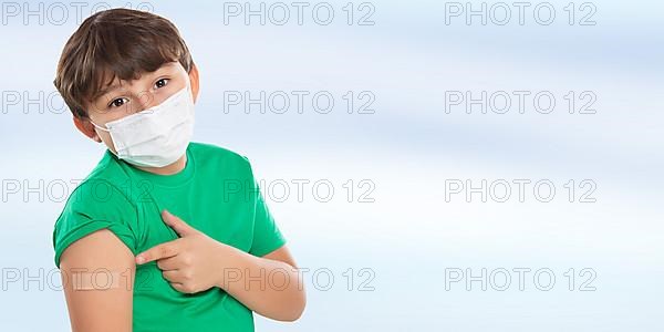 Child boy pointing finger at plaster during children vaccination mask against coronavirus corona virus text free space copyspace in Stuttgart