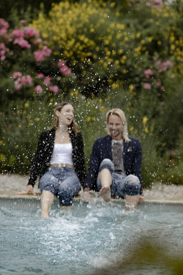 Couple sitting at the edge of the pool and splashing water