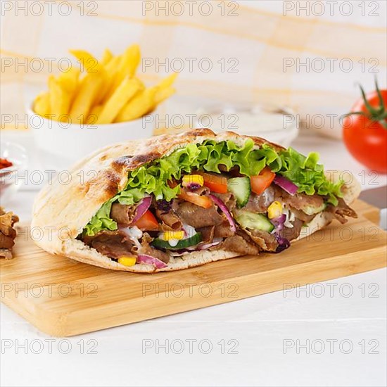 Doener Kebab Doner Kebap half fast food meal in pita bread with fries on wooden board square in Stuttgart