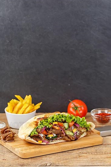 Doener Kebab Doner Kebap half fast food meal in pita bread with fries on wooden board in Stuttgart