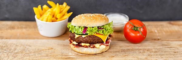 Hamburger Cheeseburger fast food meal menu with fries on wooden board Panorama in Stuttgart