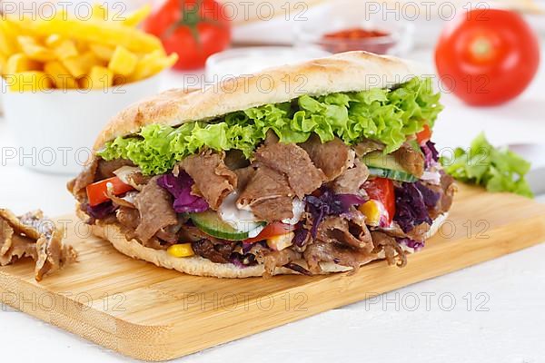 Doener Kebab Doner Kebap fast food meal in pita bread menu with fries on kitchen board in Stuttgart