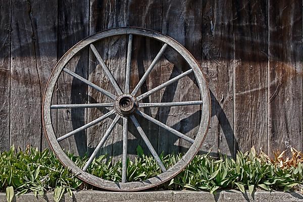 Old wagon wheel leaning against a barn wall