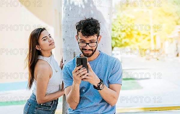 Jealous girl spying on her boyfriend's cell phone in the park