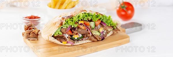 Doener Kebab Doner Kebap half fast food meal in pita bread with fries on wooden board Panorama in Stuttgart