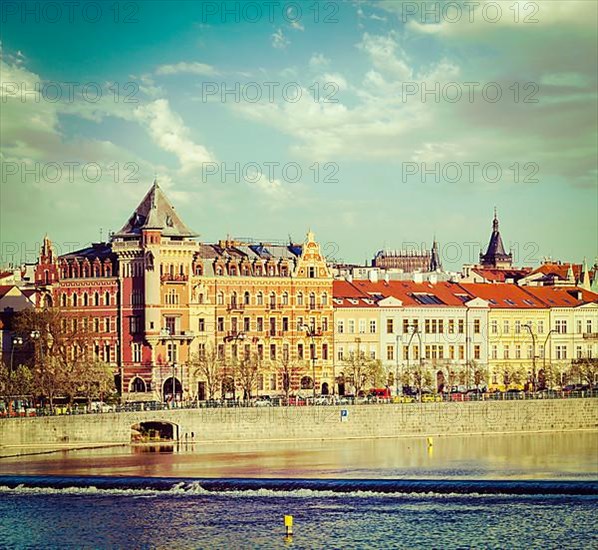 Vintage retro hipster style travel image of Prague Stare Mesto embankment view from Charles bridge on sunset. Prague