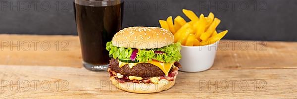 Hamburger cheeseburger fast food meal menu with fries and coke drink on wooden board Panorama in Stuttgart