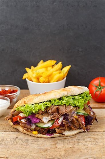 Doener Kebab Doner Kebap fast food meal in pita bread with fries on wooden board in Stuttgart