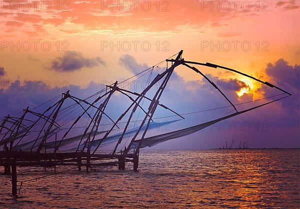 Vintage retro hipster style travel image of Kochi chinese fishnets on sunset with grunge texture overlaid. Fort Kochin