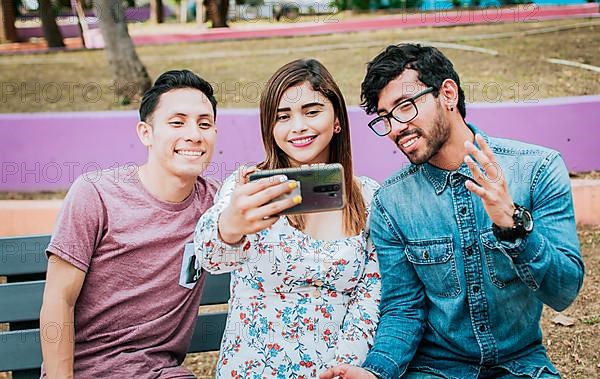 Close up of three friends taking a selfie sitting in the park