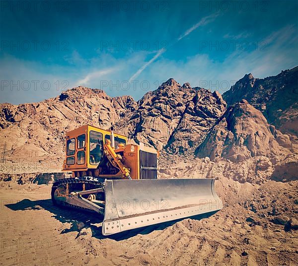 Vintage retro effect filtered hipster style travel image of Bulldozer doing road construction in Himalayas. Ladakh