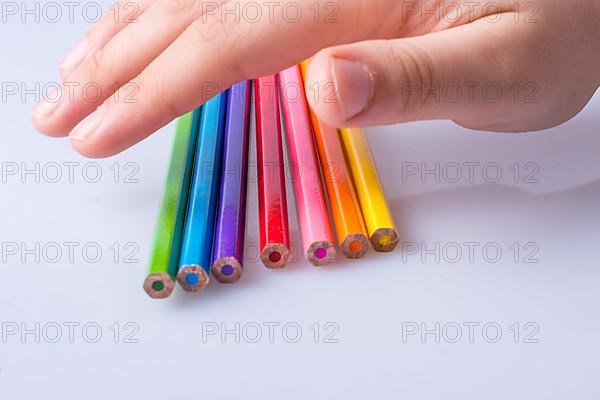 Hand holding color Pencils placed on a white background