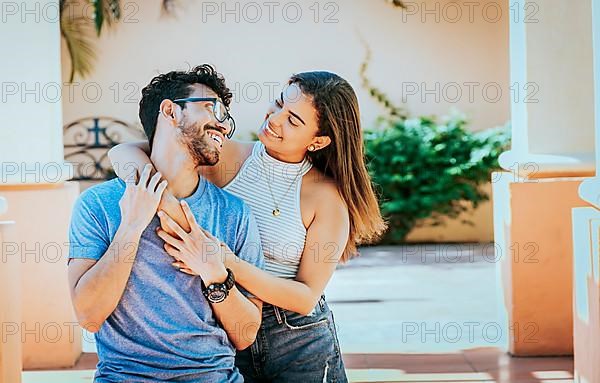 Girl hugging her boyfriend from behind. Smiling woman hugging her boyfriend from behind while he smiles at her