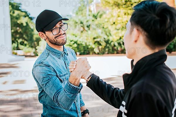 Two happy friends shaking hands in the street. Two people shaking hands on the street. Two smiling friends greet each other on the street