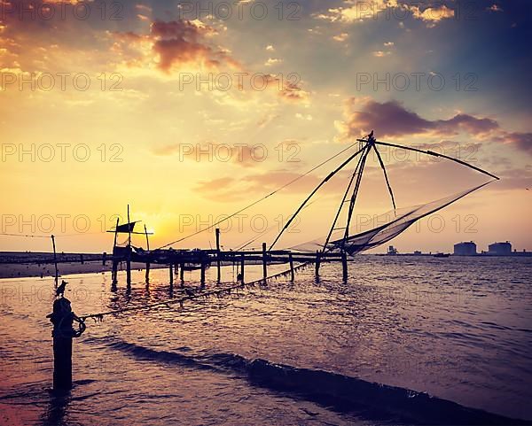 Vintage retro hipster style travel image of Kochi chinese fishnets on sunset. Fort Kochin