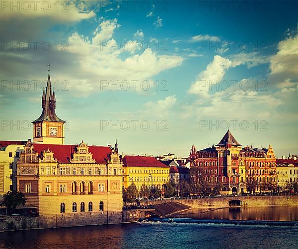 Vintage retro hipster style travel image of Prague Stare Mesto embankment view from Charles bridge on sunset. Prague