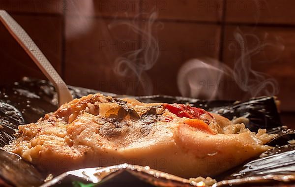 A freshly served traditional Nacatamal. Side view of Traditional Nacatamal served on banana leaf