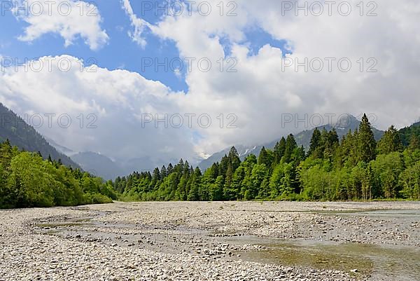 View of the Stillach river landscape and the cloud-covered mountains