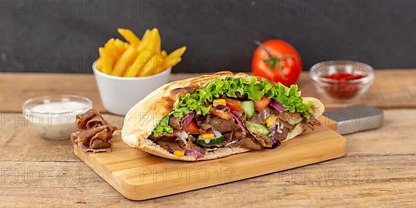 Doener Kebab Doner Kebap half fast food meal in pita bread with fries on wooden board Panorama in Stuttgart