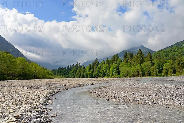 View of the Stillach river landscape and the cloud-covered mountains
