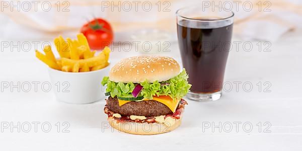 Hamburger cheeseburger fast food meal menu with fries and coke drink on wooden board Panorama in Stuttgart