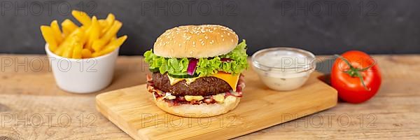 Hamburger cheeseburger fast food meal with fries on wooden board Panorama in Stuttgart