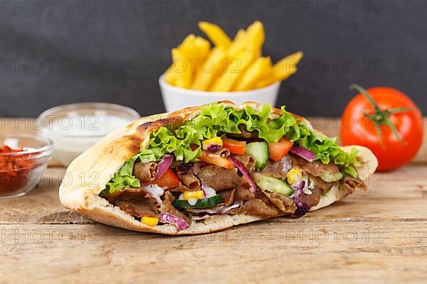 Doener Kebab Doner Kebap fast food meal in pita bread menu with fries on wooden board in Stuttgart