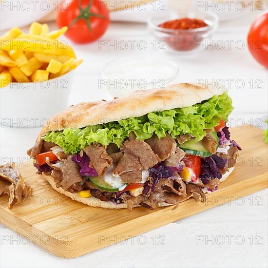 Doener Kebab Doner Kebap fast food meal in pita bread menu with fries on kitchen board square in Stuttgart