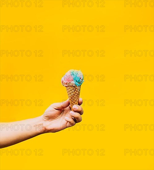 Hand holding ice cream cone on yellow background. Hand holding a waffle cone ice cream isolated. Waffle cone ice cream concept on yellow background