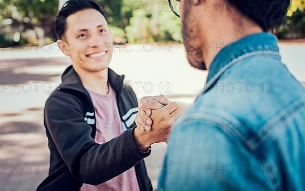 Two teenage friends shaking hands at each other outdoors. Two people shaking hands on the street. Concept of two friends greeting each other with handshake on the street